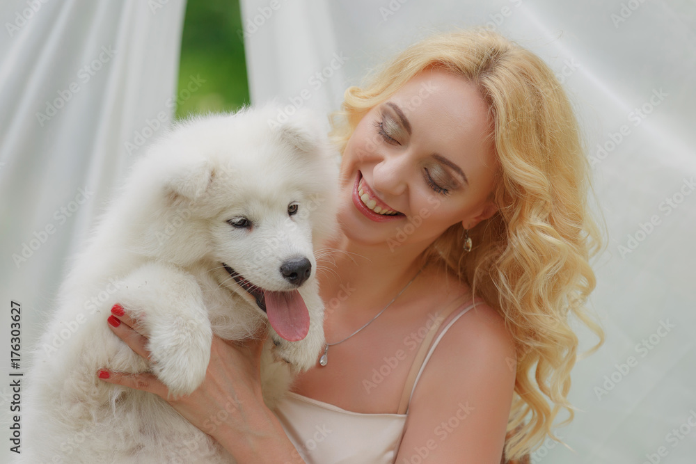 blond girl sitting on the street with a white dog in her arms blond girl sitting on the street with a white dog in her arms