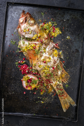 Traditional Australian barbecue rose fish with pomegranate and passion fruit as top view on a board