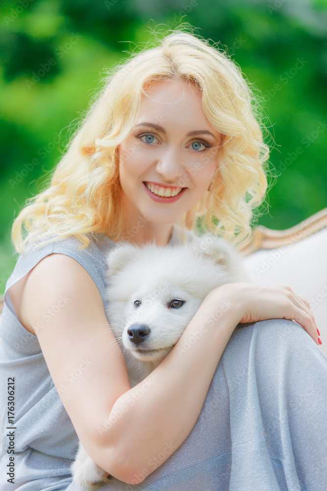 blonde girl is lying outdoors with a white dog in hands blonde girl is lying outdoors with a white dog in hands