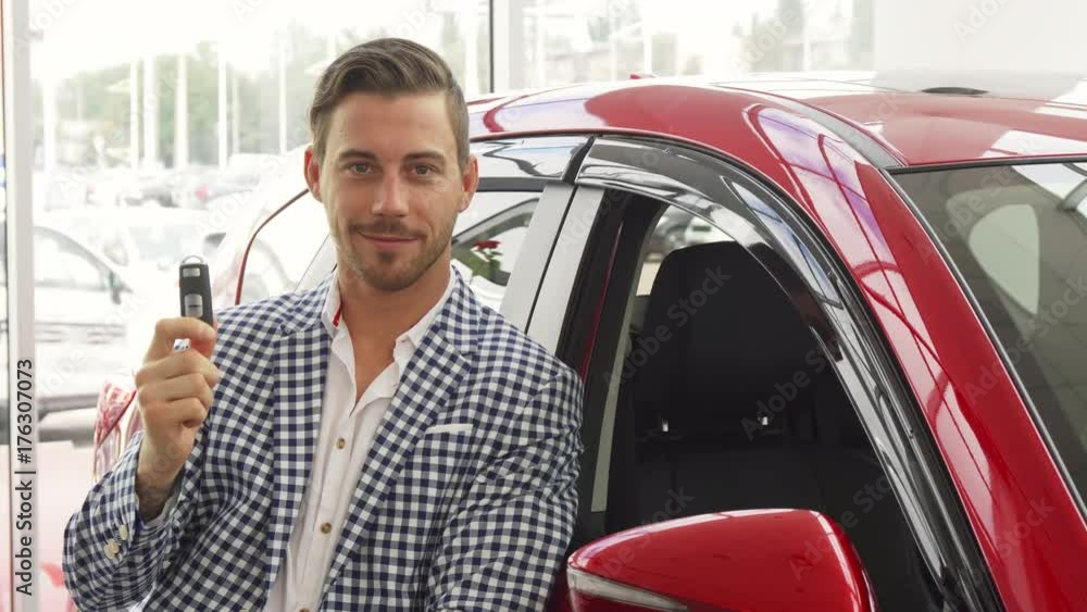 A satisfied man is standing by the new car. He bought it. He shows the keys of this automobile. He looks very pleased and happy A satisfied man is standing by the new car. He bought it. He shows the keys of this automobile. He looks very pleased and happy