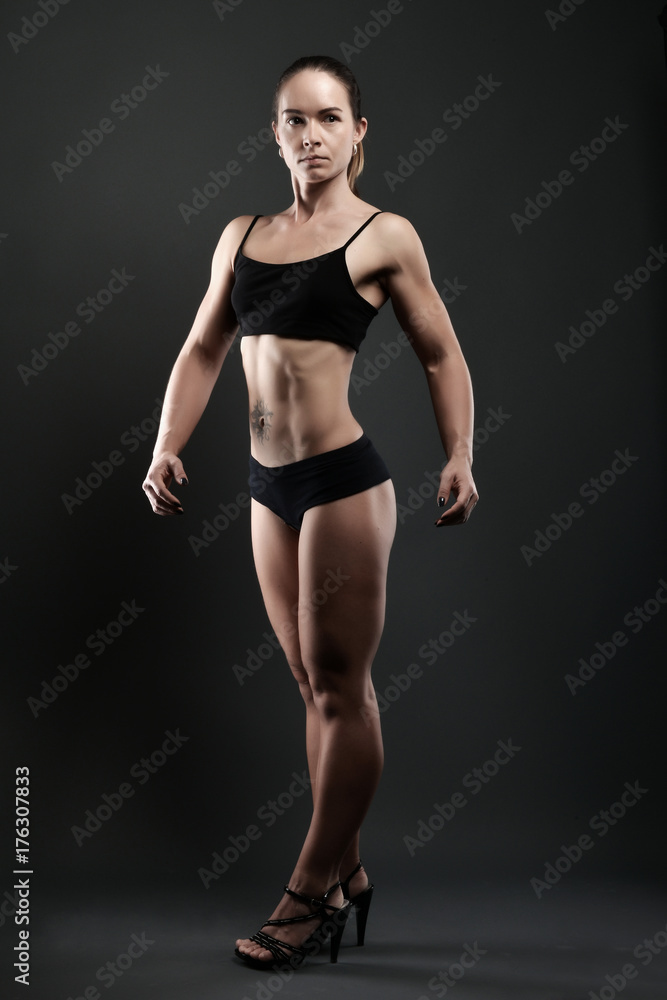 athletic woman showing muscles on dark background