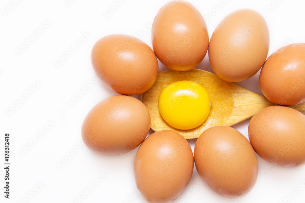 Raw egg yolk on wooden spoon between eggs on white background Raw egg yolk on wooden spoon between eggs on white background