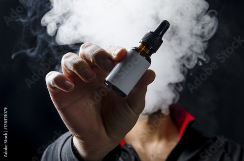 vape e liquid bottle hold by a young man with smoke cloud for electronic cigarette, Isolated eliquid brown bottle for ecig  white empty white label. 