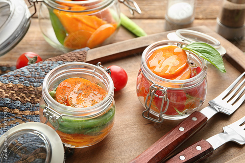 Jars with tasty carrot salad on wooden board