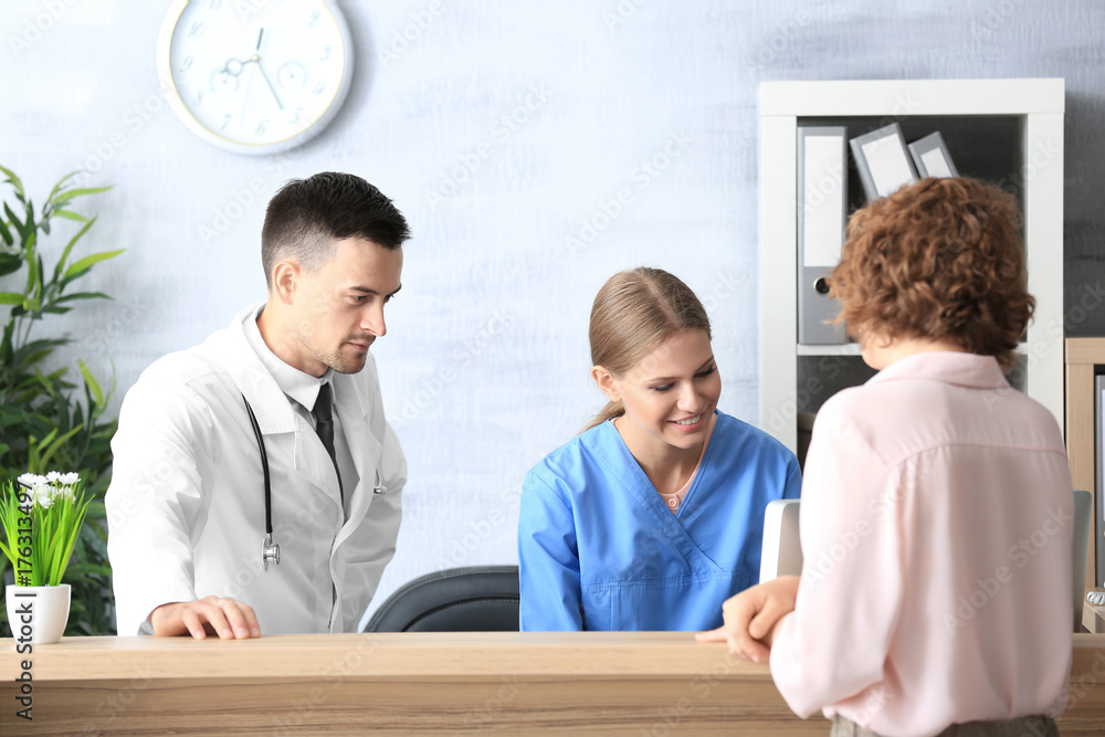 Fototapeta premium Receptionist and doctor with client in hospital