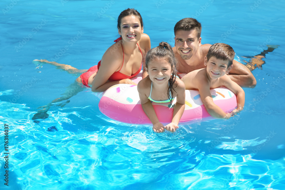 Happy family with inflatable ring relaxing in swimming pool