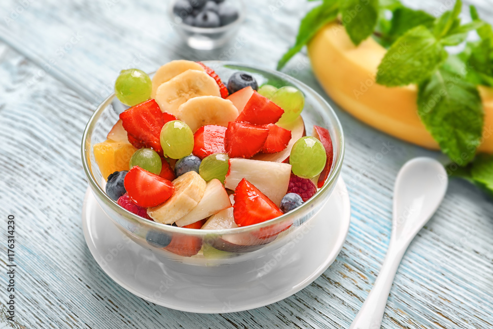 Bowl with yummy fruit salad on wooden table Bowl with yummy fruit salad on wooden table