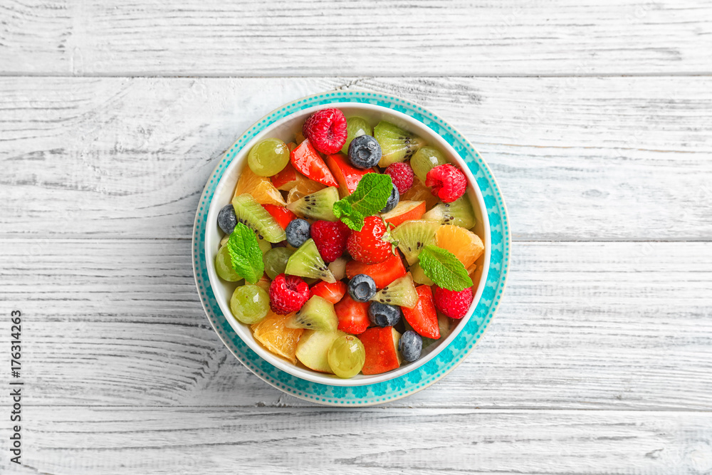 Bowl with yummy fruit salad on wooden table Bowl with yummy fruit salad on wooden table