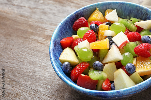 Bowl with yummy fruit salad on wooden table