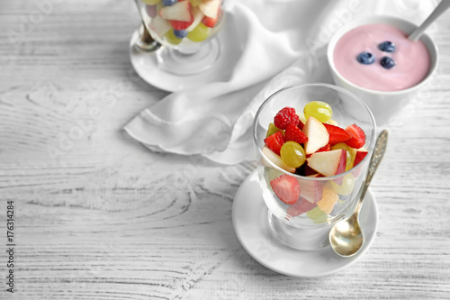 Glass with yummy fruit salad on wooden table