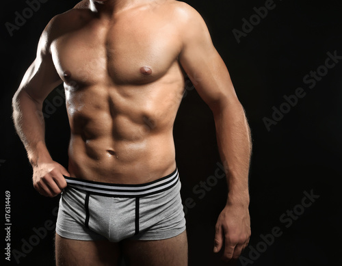 Muscular man in underwear on dark background