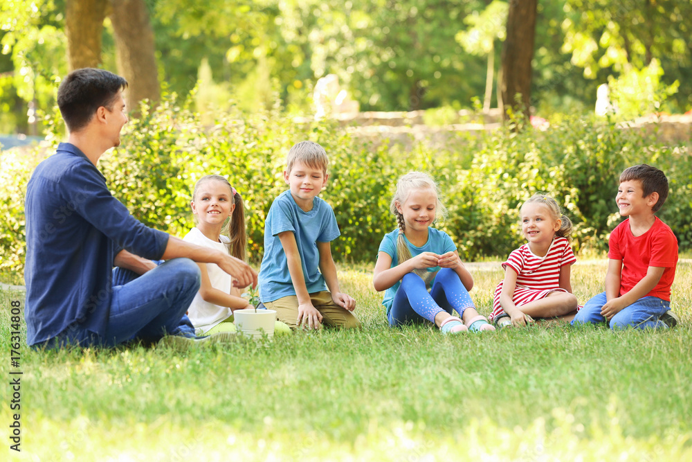 Group of children with teacher in park on sunny day