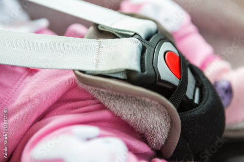 Buckle of a child's safe seat in the car; baby sitting in the seat buckled