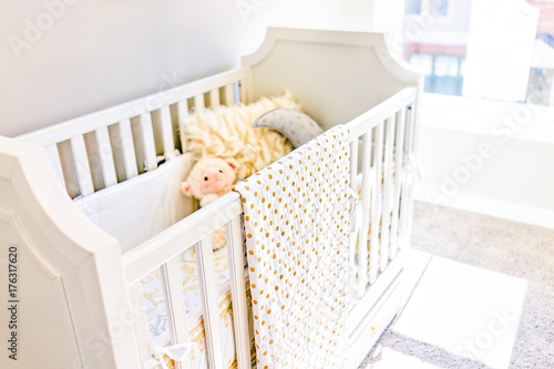 Fototapeta Naklejka Na Ścianę i Meble -  Closeup of bright yellow baby crib in nursery room with toys and pillow in model staging home, apartment or house