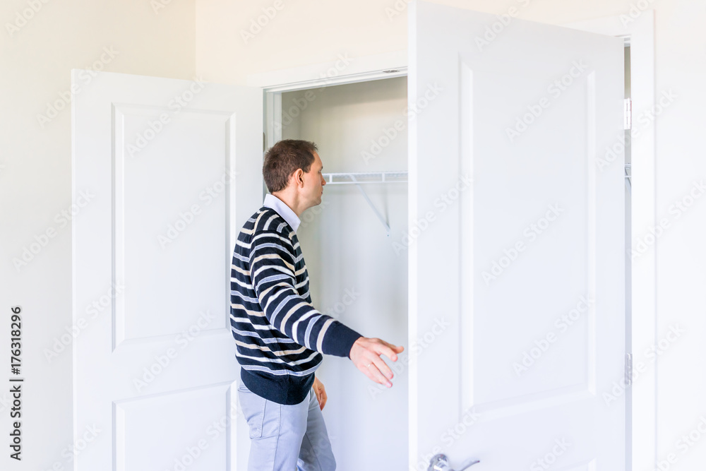 Young man checking looking inside small closet in new room after or before moving in, during open house