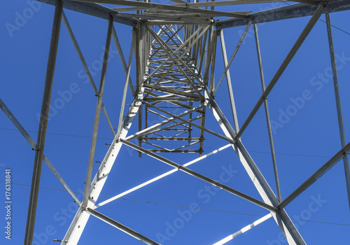 Supports high-voltage power lines against the blue sky. View fro
