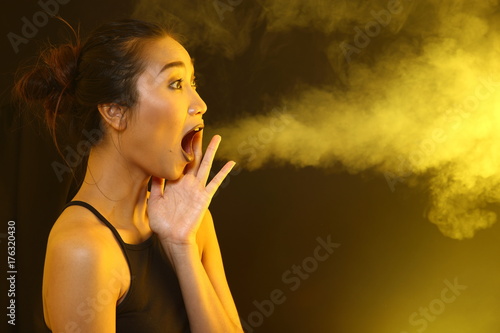 Smoke Tan Skin Asian Woman black hair dark lip with Dense Fluffy Puffs of White Smoke and Fog on dark Background