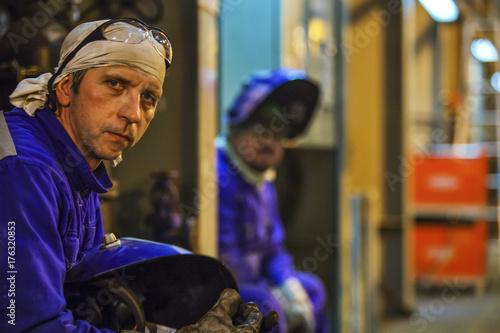 Workers fitters and welders in protective clothing and a helmet.