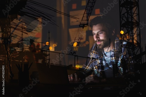Composite image of man using laptop against building