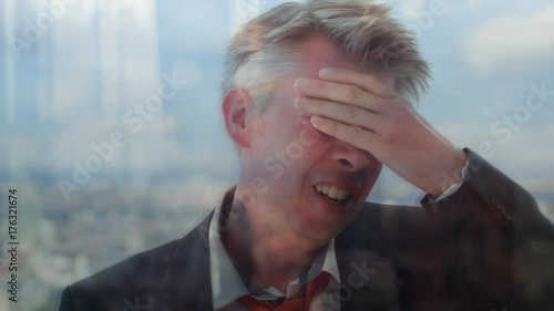 Reflection of a distressed businessman with a cityscape behind
