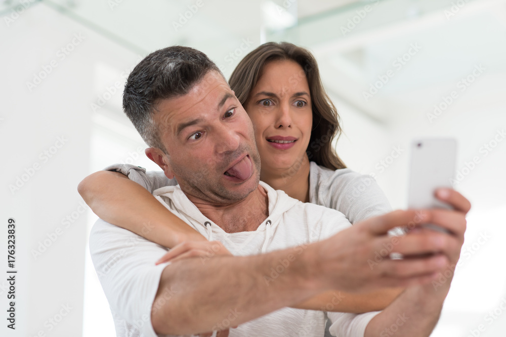 Fototapeta premium happy couple using mobile phone at home