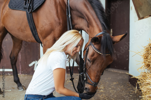 Beautiful young woman enjoying with her horse outdoors at ranch.