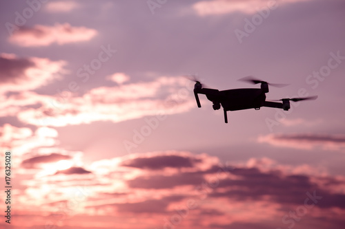 Silhouette of drone hovering in a colorful sunset. Toned image. Soft focus