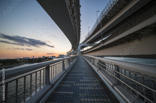 View of a beautiful sunset behind the Tokyo skyline. Photo taken from the Rainbow Bridge which connect Tokyo to Odaiba Island.