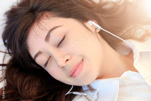Happy young woman listening to the music on the bed. concept fot healthy and music business