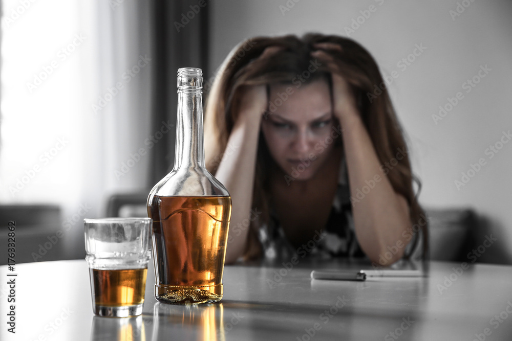 Glass with bottle of alcohol drink and drunk woman on background Glass with bottle of alcohol drink and drunk woman on background