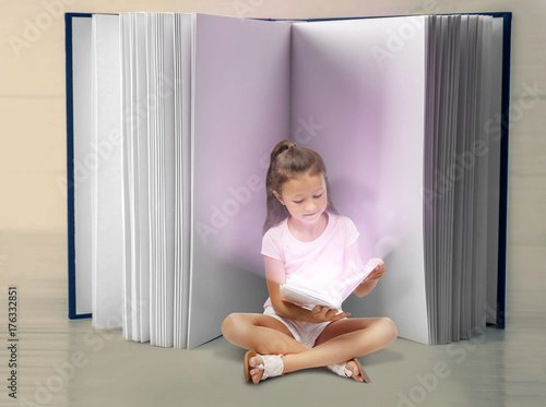 Cute little girl reading bo...