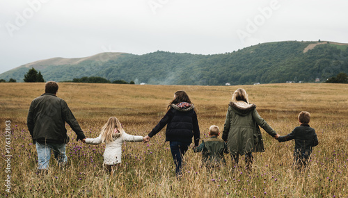 Rear view of caucasian family walking together in the field