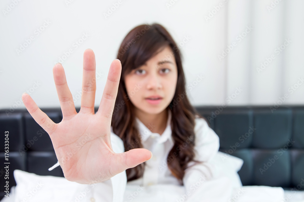 Portrait of a young attractive woman showing stop sign with hand on her bedroom Portrait of a young attractive woman showing stop sign with hand on her bedroom