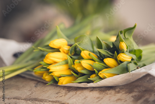 Yellow tulips flowers bouquet on a wooden table