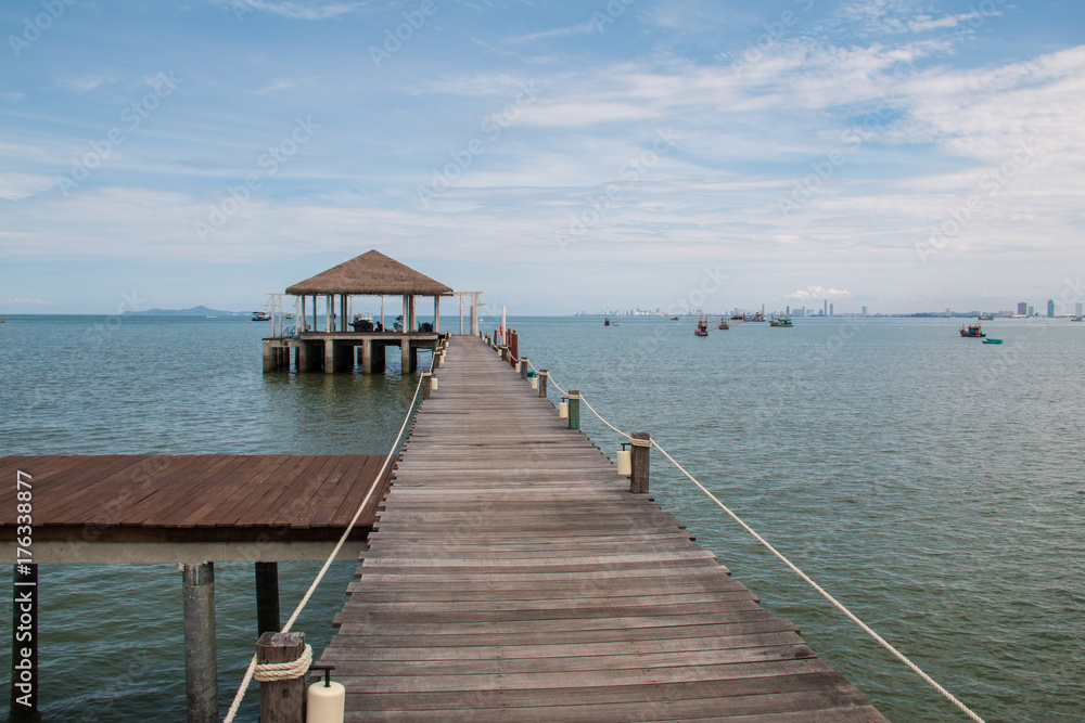 Boardwalk leads out onto the sea with beautiful blue sky background in Thailand.