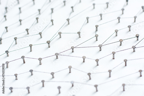 nails in white paper simulation network. linked together by black cotton
