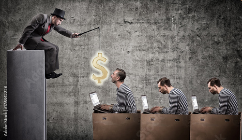 A greedy businessman motivates office workers with a salary. Office slavery concept. photo