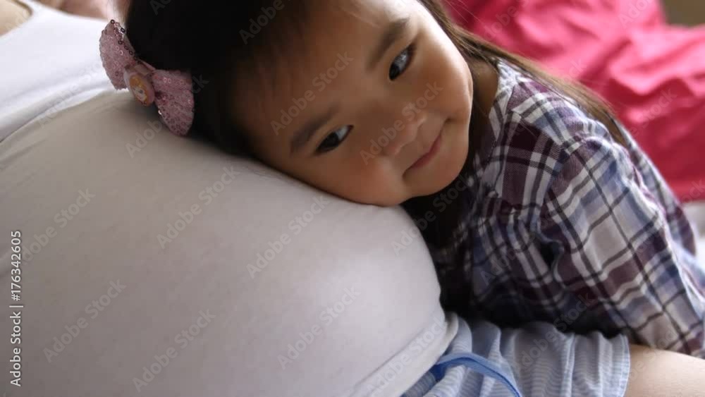 A little asian girl rubs her mother's pregnant belly and then listens to her belly A little asian girl rubs her mother's pregnant belly and then listens to her belly