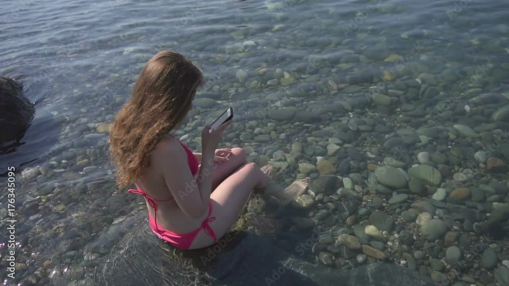 A girl on the beach with her smartphone in slow motion A girl on the beach with her smartphone in slow motion
