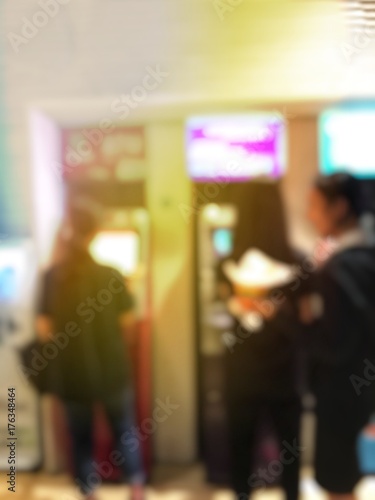 blurred image of people line up to use Banking Machine or ATM(Automatic Teller Machine) to Deposit in city at night time and can be illustration to article of people use atm