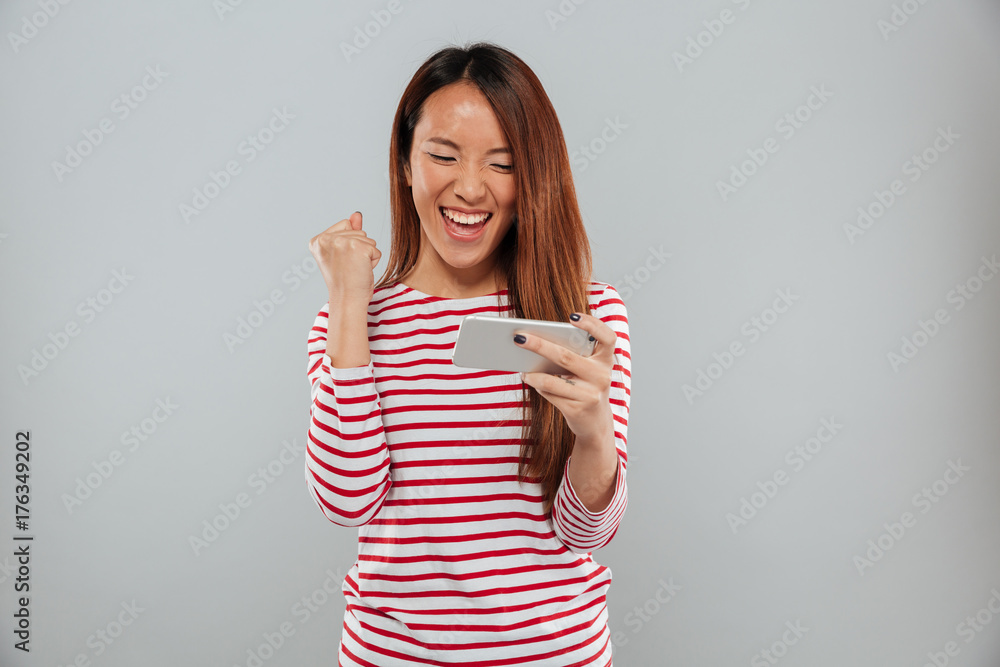 Excited young asian lady play games by phone Excited young asian lady play games by phone