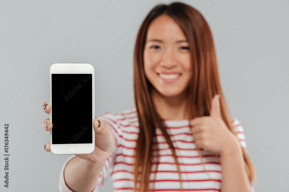 Smiling young asian woman showing display of phone