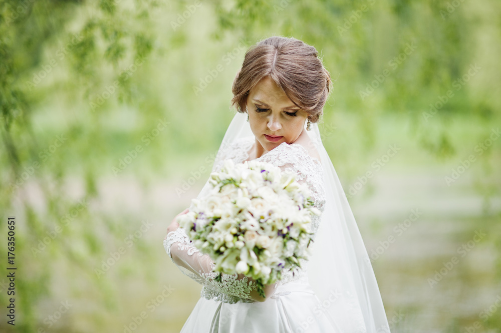 Portrait of a beautiful young bride posing with a bouquet outdoor on her own. Portrait of a beautiful young bride posing with a bouquet outdoor on her own.