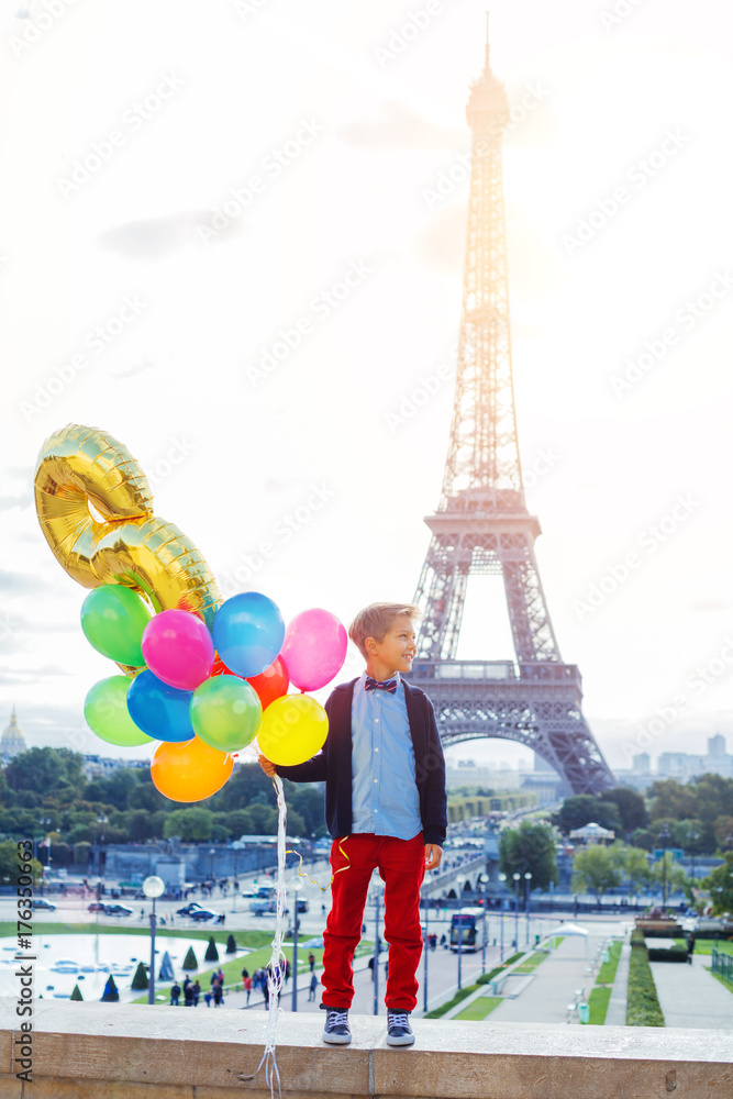 Boy with bunch of colorful balloons in Paris near the Eiffel tower.