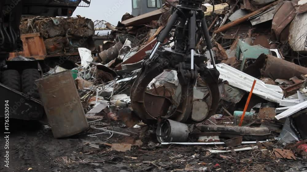 Sorting and loading of scrap metal./Excavator is loading scrap metal junk into a bin at a garbage dump or recycling center. Sorting and loading of scrap metal./Excavator is loading scrap metal junk into a bin at a garbage dump or recycling center.