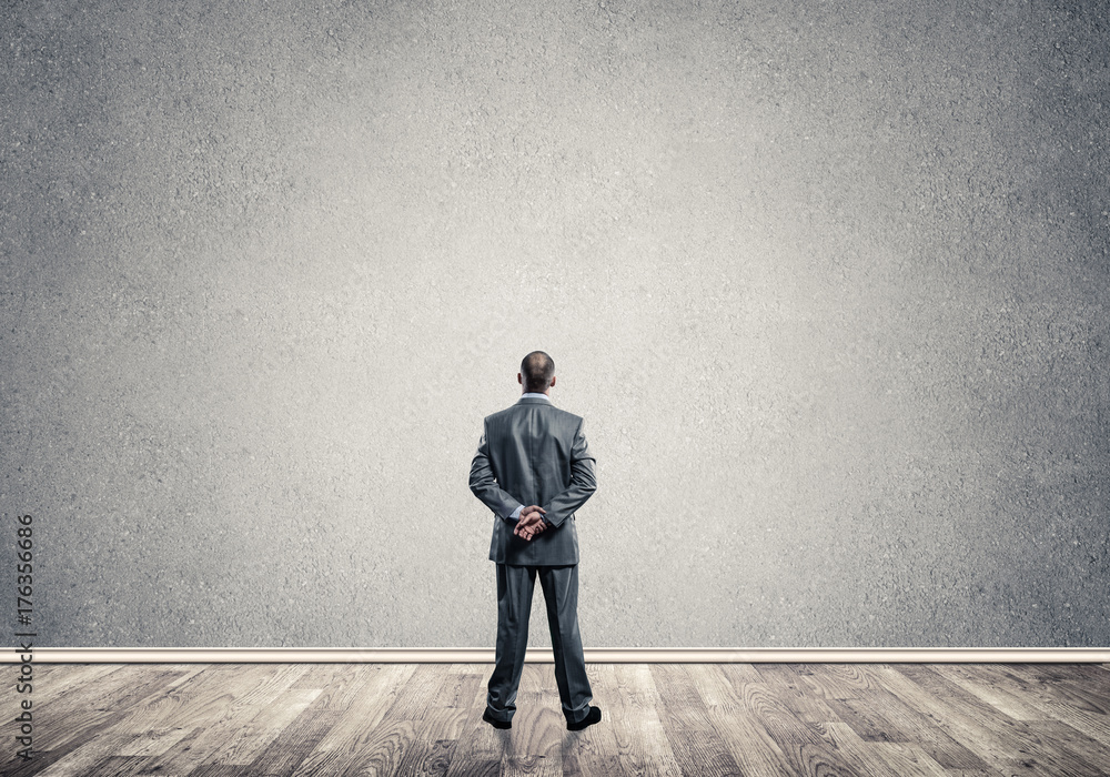 Businessman with hands behind his back and looking at blank conc Businessman with hands behind his back and looking at blank conc