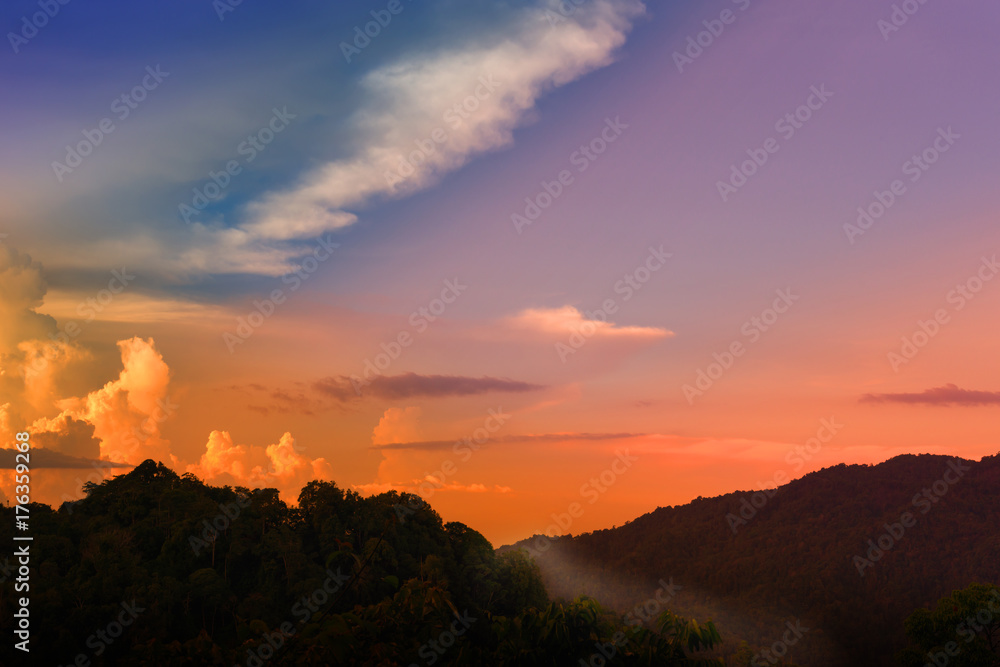 Twilight sky over the mountain. Beautiful twilight color shining on sky and cloud on the high mountain range at sunset with forest silhouette in foreground. Twilight sky over the mountain. Beautiful twilight color shining on sky and cloud on the high mountain range at sunset with forest silhouette in foreground.
