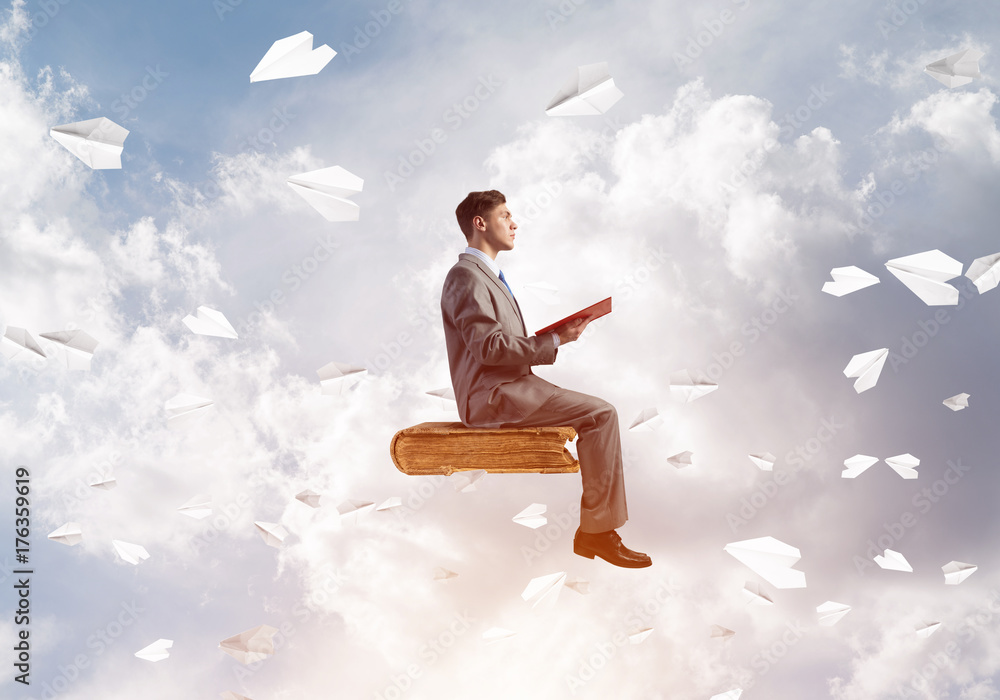 Businessman or student reading book and paper planes flying around Businessman or student reading book and paper planes flying around