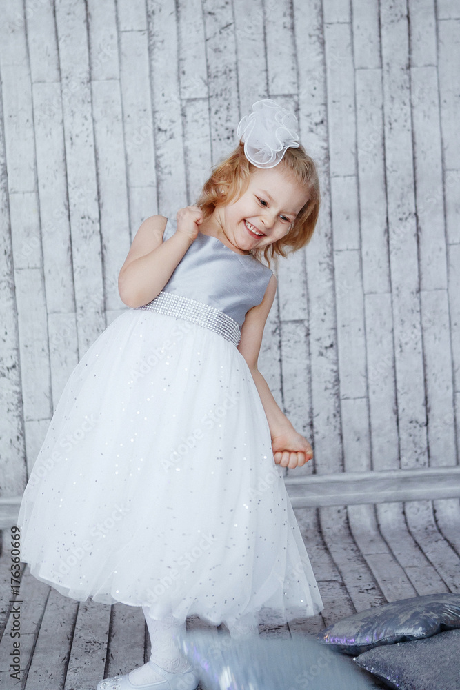 little girl in beautiful white dress on a light wooden background. Shine, silver, Xmas little girl in beautiful white dress on a light wooden background. Shine, silver, Xmas