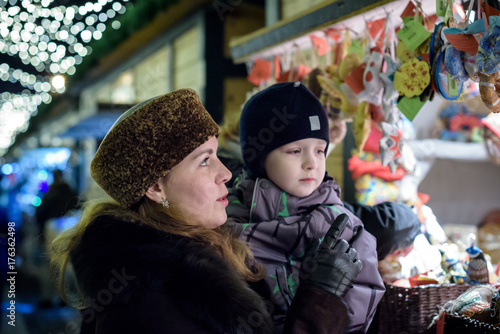 Happy family spend time at a Christmas street market fair in the old town of Salzburg, Austria. Holidays, , concept. Mother and son winter outdoor among decorations